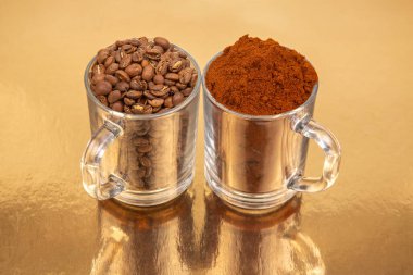 Altın bir zemin üzerinde iki cam bardak yakın plan, biri tamamen kavrulmuş kahve çekirdekleri ile dolu, diğeri ise zengin kahve çekirdekleri ile. Mutfak ya da içecek kavramları için ideal
