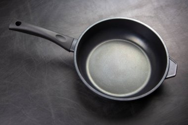 Siyah bir tencere, kullanıma hazır şık bir mutfak tezgahına oturur. Pürüzsüz yüzeyi ve dayanıklı sapı evde çeşitli yemek hazırlıkları için uygun olduğunu gösteriyor..