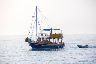 Geleneksel ahşap bir tekne, Türk kıyı şeridinin sakin sularında sorunsuzca süzülüyor.
