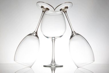 Üç zarif şarap kadehi sanatsal olarak yerleştirilmiştir. Bir tanesi ortada, iki tanesi de baş aşağı durarak parlak bir arkaplanda büyüleyici yansımalar ve şekiller oluşturur..