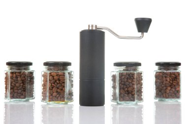 Bir el yapımı kahve öğütücüsü çeşitli kavrulmuş kahve çekirdekleri ile dolu dört cam kavanozun arasında duruyor. Düzenleme kahve meraklıları için mükemmel bir düzenek sergiliyor..