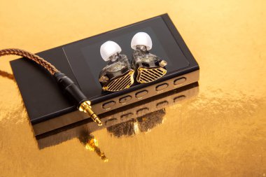 Yüksek kaliteli kulaklıklar, parlak bir arka planda, dijital bir ses çaların yanında tasarım ve işçiliklerini ön plana çıkarıyor. Ortam lüks bir his yaratıyor, odiyofiller için ideal..