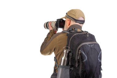 Uzakta duran bir fotoğrafçı, profesyonel bir kamerayla canlı manzaralar yakalamaya odaklanmış. Sırt çantasıyla birlikte, mükemmel çekim için açık havayı keşfetmeye hazırlanıyor..