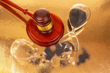 Yargı tokmağı, zaman ve adalet arasındaki ilişkiyi sembolize eden parçalanmış bir kum saatiyle birlikte yansıtıcı bir yüzeye dayanır. Sahne, aciliyet ve sonuç hissi veriyor..