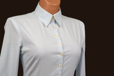 Açık mavi çizgili bir gömlek, detaylarını ve kumaş dokusunu vurgulayan koyu bir arka plana yerleştirilmiş klasik bir tasma ve düğmeli tasarım içeren bir mankenin üzerinde sergilenir..