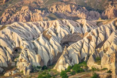 Cappadocia 'nın eşsiz jeolojik oluşumlarının nefes kesici bir görüntüsü dalgalanan tepeler ve sıcak ışıkla yıkanmış kaya oluşumlarını içerir..