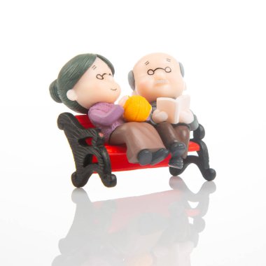 Minyatür bir çift, küçük kırmızı bir bankta birlikte huzurlu bir öğleden sonranın tadını çıkarıyor. Kadın elinde iplik tutarken, adam kitap okuyor ve hoş bir ev sahnesi sergiliyor..