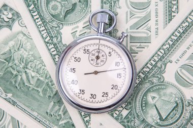 Bir kronometre, zaman ve para arasındaki ilişkiyi sembolize eden 1 dolarlık banknotların üzerine yerleştirilir..