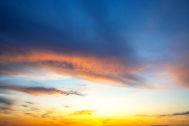 Gün batımında, gökyüzü turuncu ve mavinin canlı tonlarıyla boyanır. Yumuşak bulutlar sürükleniyor, sakin bir atmosfer yaratıyor. Rahatlamak ya da doğayı düşünmek için mükemmel..