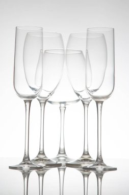 Zarif saplı beş sıra boş şarap kadehi, parlak bir masaya mükemmel yansıyor, konukseverlik, etkinlik veya şarapla ilgili görseller için ideal..