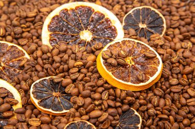 Kavrulmuş kahve çekirdekleri ile karıştırılmış kurutulmuş turunçgil dilimlerinin sıcak ve davetkar görüntüsü, rustik ve aromatik bir özü yakalıyor. kahve aroması ve tat tanımlayıcıları