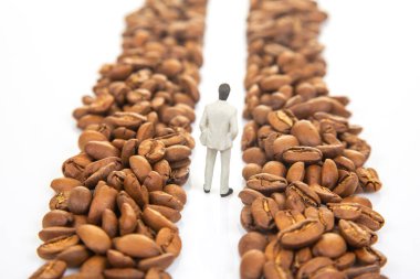 Kahve çekirdekleri arasında yürüyen takım elbiseli minicik bir figürün yaratıcılığı kahve ticaretindeki profesyonel yolculuğu sembolize ediyor.