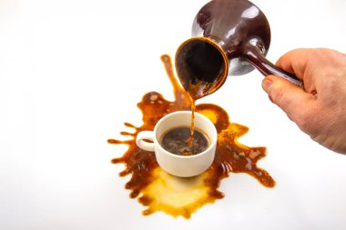 Geleneksel bir seramik çaydanlıktan beyaz bir fincana zengin bir kahve döken bir el, el değmemiş beyaz bir arka planda çarpıntı yaratarak sabah talihsizliğinin özünü yakalar..