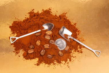 İki metal küreği öğütülmüş kahveye yakın plan, içinde tüm fasulyeler ve parlak altın arka planda bir ABD çeyreği var, kahve malzemesi tasviri için ideal.