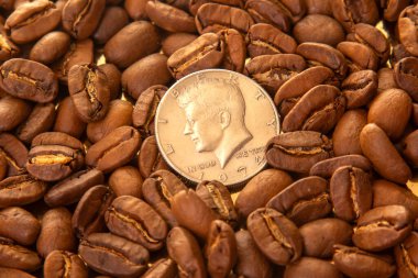 Kavrulmuş kahve çekirdekleri ve altın yansıtıcı arka planda bir ölçek için Amerikan parasıyla zengin kahverengi renkleri ve dokuları sergileniyor. Kahve ve boyut karşılaştırması için mükemmel..