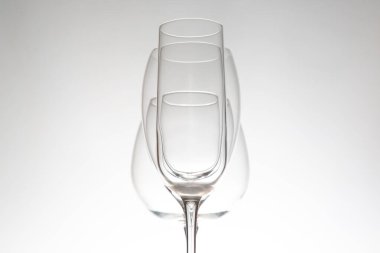 Üç kristal berraklığında çeşitli şekillerde şarap kadehi yan yana duruyor. Yansımaları parlak bir yüzey üzerinde parıldıyor. Lüks bir yaşam tarzı görüntüsü için ideal..