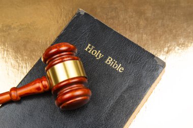 Altın bir yüzey üzerinde altın bir şerit bulunan ahşap bir tokmak, hukukun, inancın ve yargının kesişimini sembolize ediyor.. (