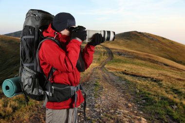 Kırmızı ceketli bir seyahat fotoğrafçı doğa fotoğraflarını çekiyor