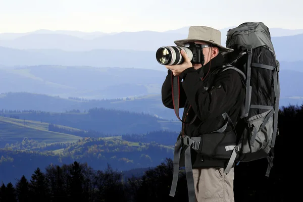 Оборудованный путешественник фотограф фотографирует природу — стоковое фото