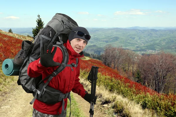 Viajante feliz equipado com um casaco vermelho na encosta levantada — Fotografia de Stock