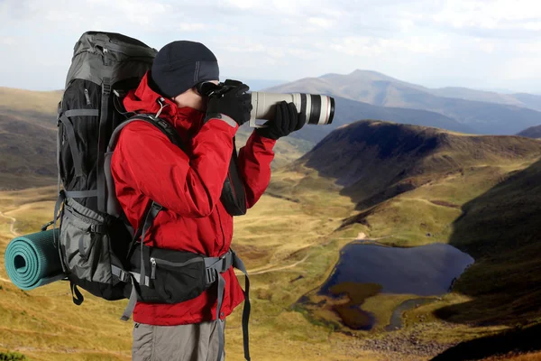 Фотограф-путешественник в красной куртке фотографирует природу — стоковое фото