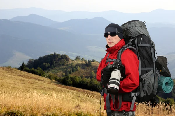 Traveler photographer in the red jacket on the mountain slope Royalty Free Stock Photos