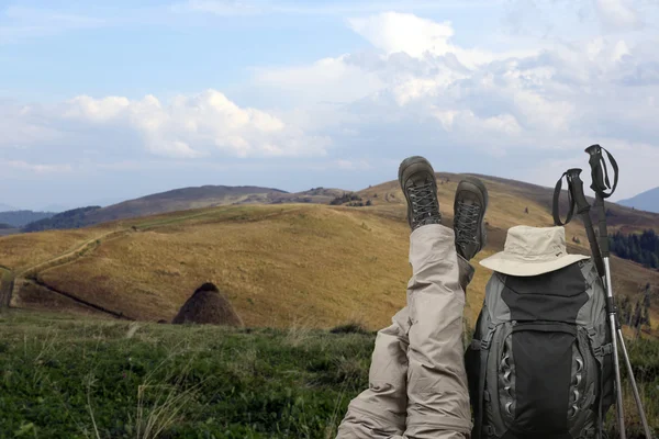 Turista cruzou as pernas perto de uma mochila na natureza — Fotografia de Stock