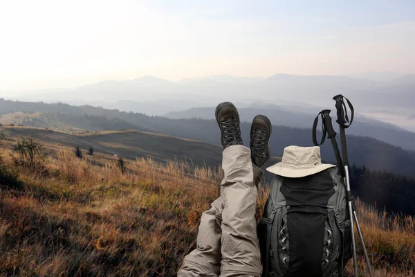 Туристка скрестила ноги возле рюкзака на природе — стоковое фото