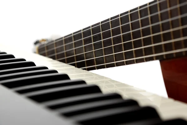 Клавіші для фортепіано та класична гітара крупним планом на білому тлі — стокове фото