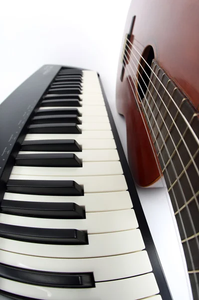 Клавіші для фортепіано та класична гітара крупним планом на білому тлі — стокове фото