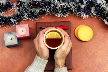 bir fincan çay ile iki el üstünde belgili tanımlık Noel defter vardır