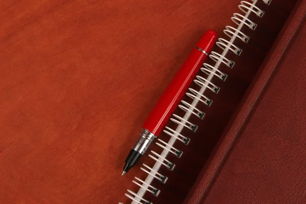 Portátil y un bolígrafo rojo acostado en un escritorio de madera — Foto de Stock