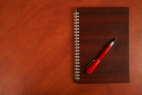 Portátil y un bolígrafo rojo acostado en un escritorio de madera —  Fotos de Stock