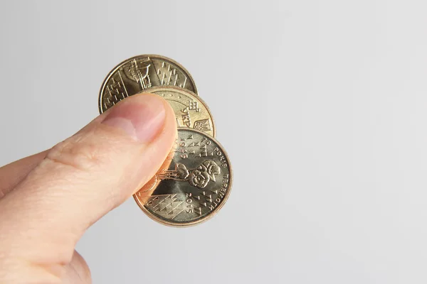fingers holding three Ukrainian coins on a light background