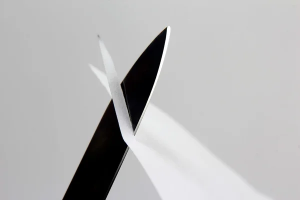 Klinge eines scharfen Messers quer über das weiße Papier geschnitten — Stockfoto