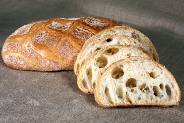 Beyaz ekmek saman gri keten masa örtüsü üzerinde yatan dilimlenmiş