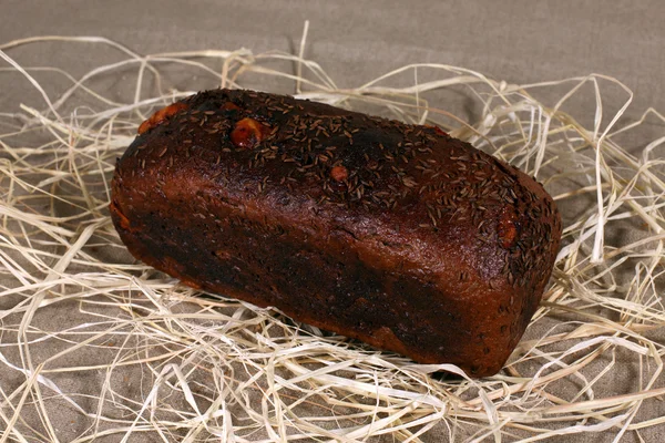 Pan marrón relleno con queso tirado en paja sobre lino gris — Foto de Stock