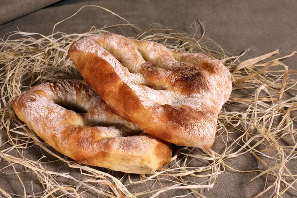 Dois pão branco deitado em palha na toalha de mesa de linho cinza — Fotografia de Stock