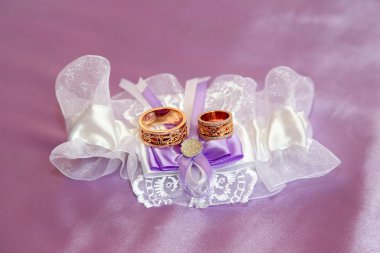 wedding rings lie on beautifully embellished fabrics clipart