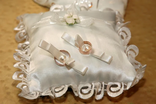 Обручальные кольца лежат на красивой белой подушке — стоковое фото