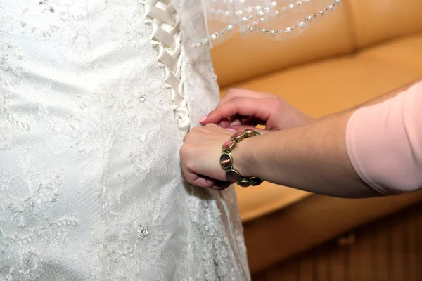 Bridesmaids help her put on wedding dress — Stock Photo, Image