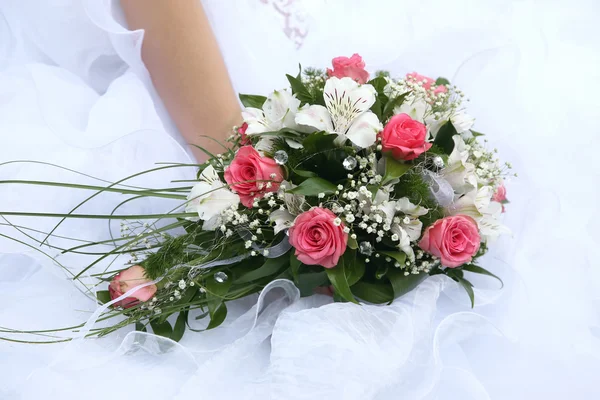Свадебный букет невесты на фоне ее платья — стоковое фото
