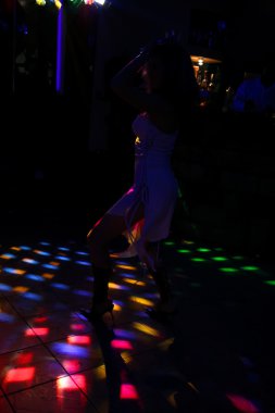 gece kulübünde beyaz elbiseli bir dans eden kız silüeti