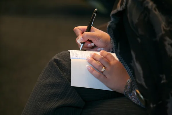 Mujer hace una nota en primer plano cuaderno — Foto de Stock