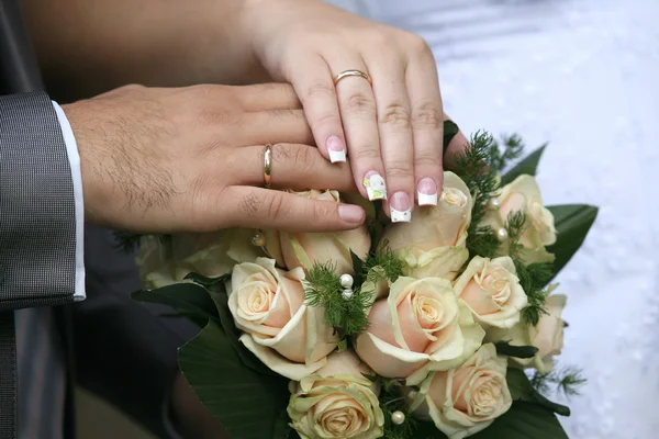 Mãos de noiva e noivo perto do buquê de casamento — Fotografia de Stock