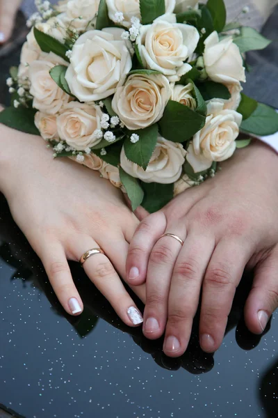 Mãos de noiva e noivo perto do buquê de casamento — Fotografia de Stock