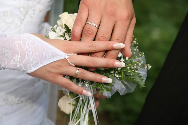 Mãos de noiva e noivo perto do buquê de casamento — Fotografia de Stock