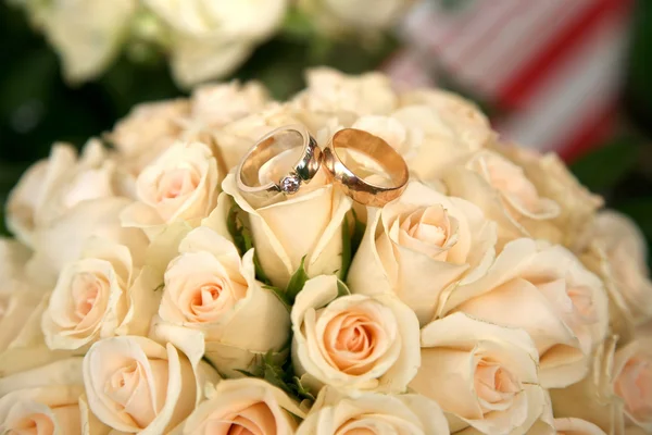 Anillos de boda de oro se encuentran en un ramo de rosas — Foto de Stock