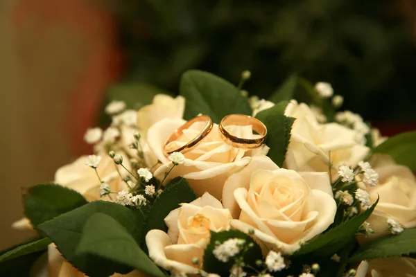Золотые обручальные кольца лежат на букете роз — стоковое фото