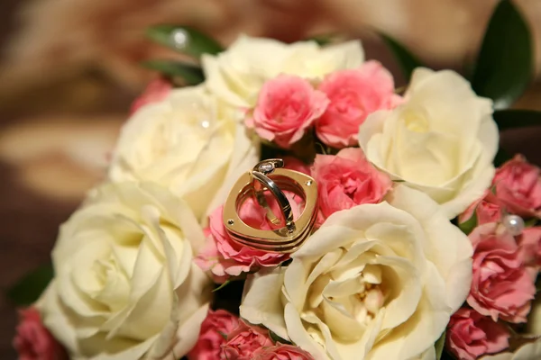 Anéis de casamento de ouro jazem em um buquê de rosas — Fotografia de Stock